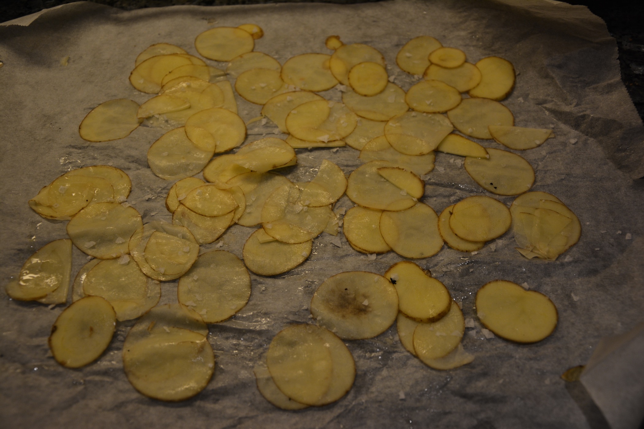 Lägg tunt hyvlad potatis på ett bakplåtspapper