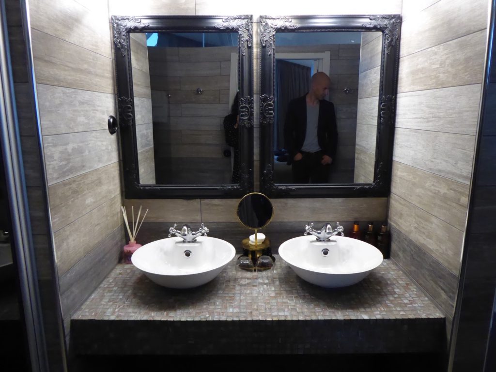 Stort badrum med två handfat, bubbelppol, två duschar och toalett. 